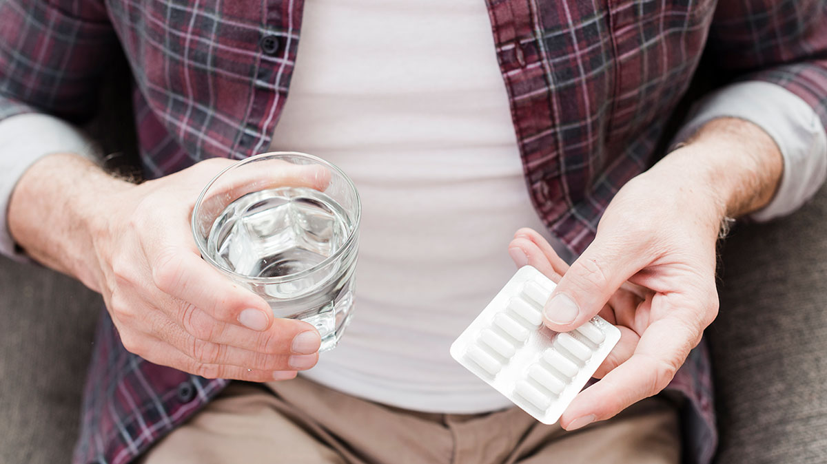 Older adult managing multiple medications, highlighting the risks of complex health plans.