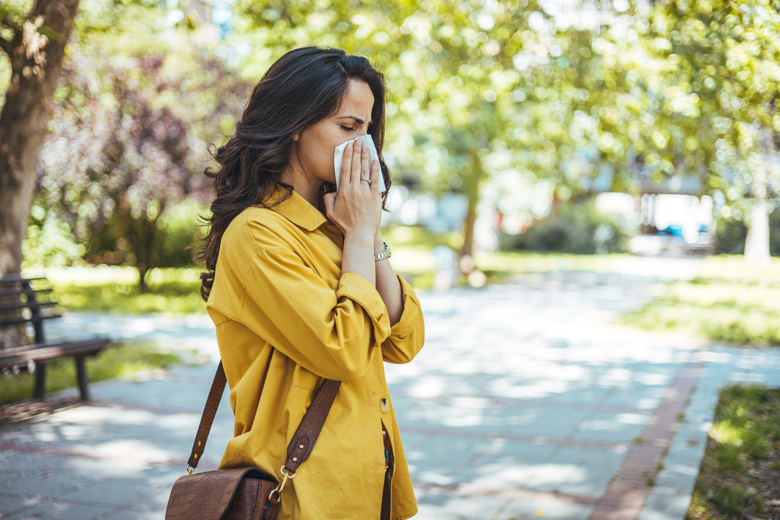 woman sneezing outdoors showing need for immune system support