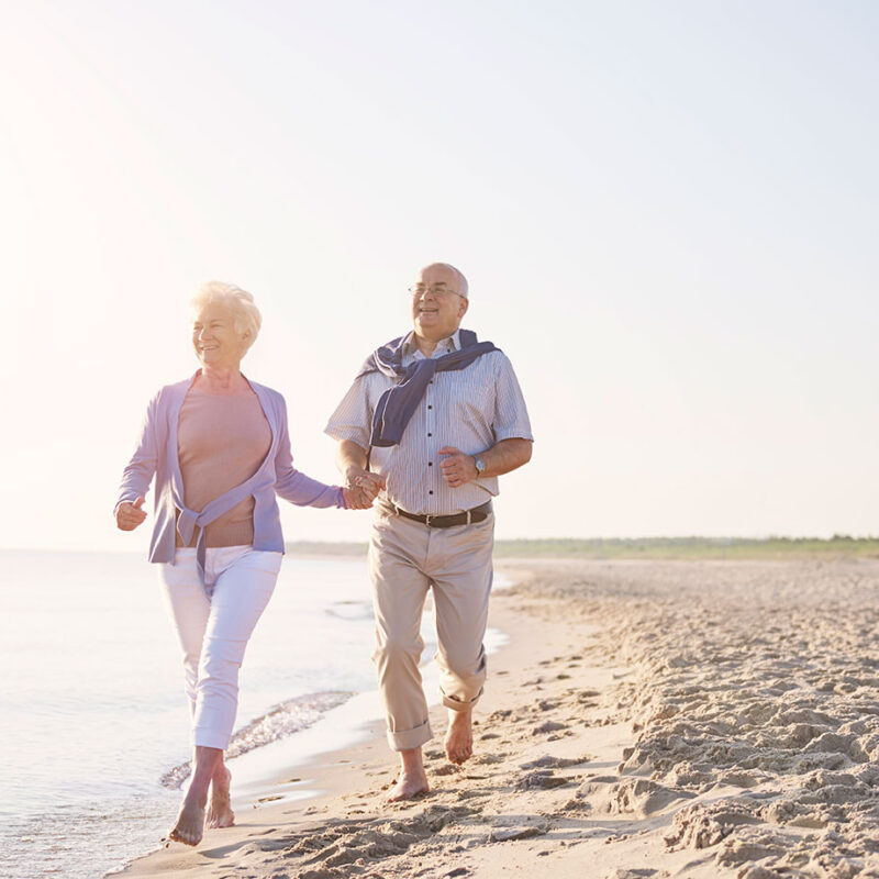 Older couple walking on the beach as part of an active lifestyle supporting healthy aging.