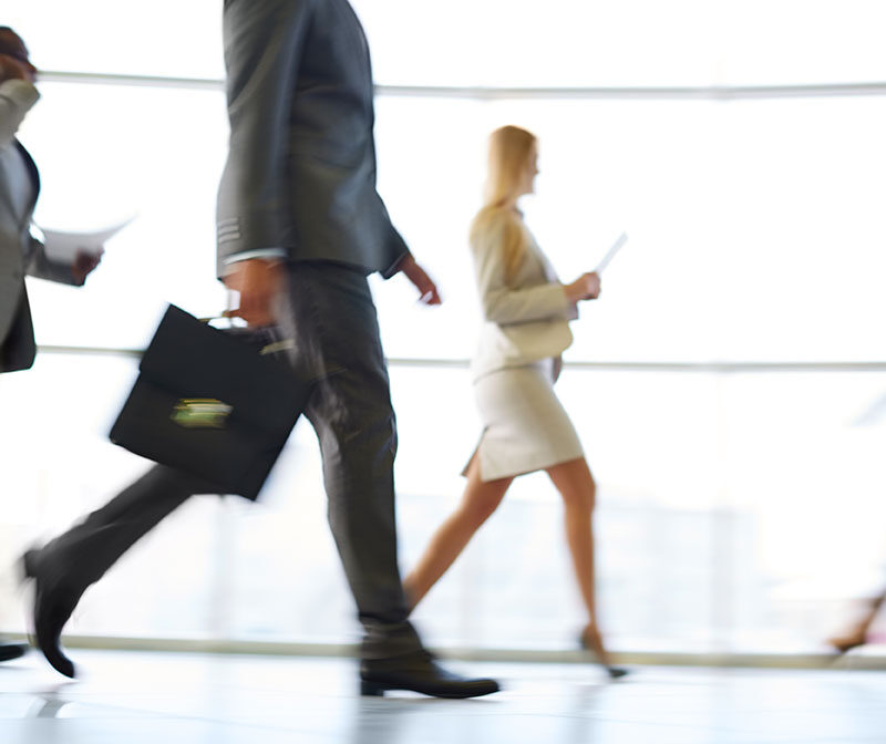 Business professionals walking quickly, symbolizing the need for healthcare for busy professionals.
