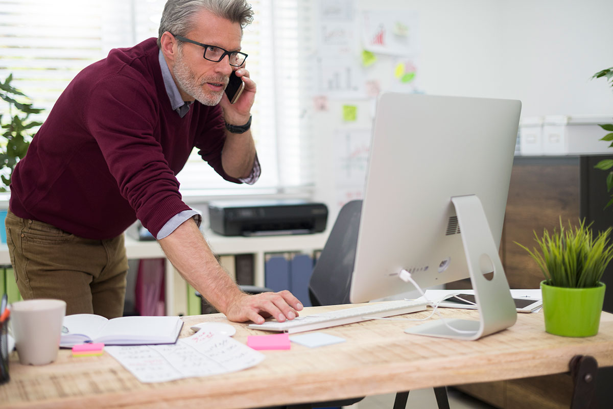 Busy professional multitasking at his desk, highlighting the importance of healthcare for busy professionals.